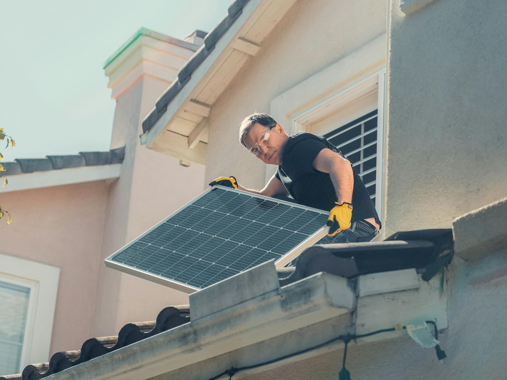 Man installing solar panels on a house