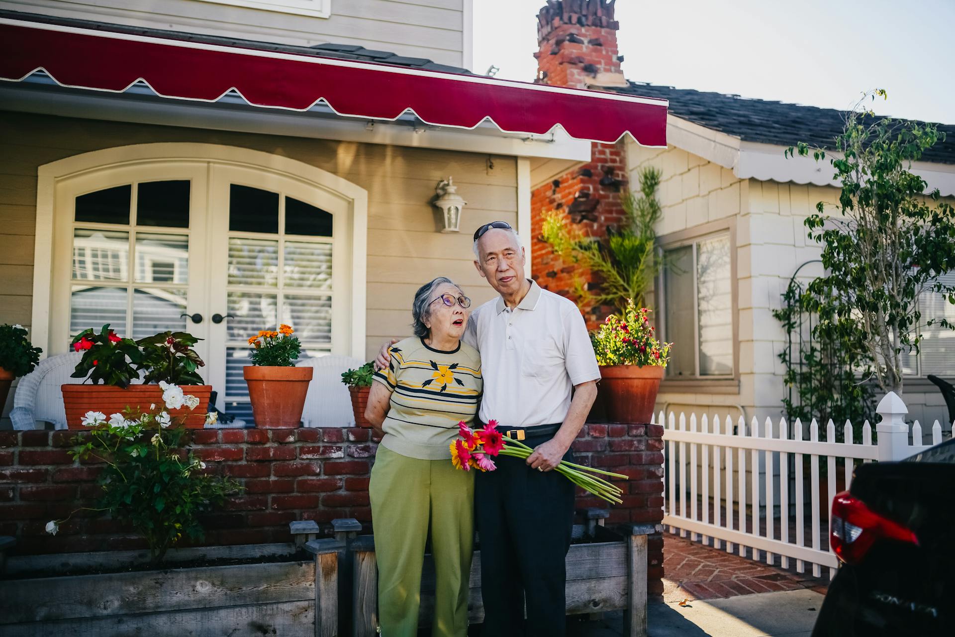 Senior citizens standing next to a house